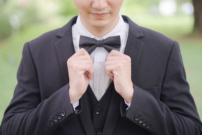 Midsection of businessman wearing tuxedo while standing outdoors