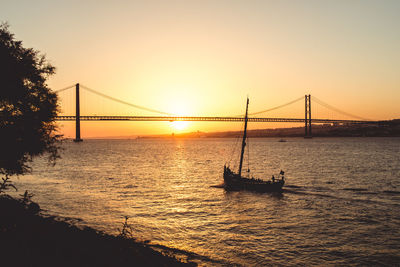 Silhouette of suspension bridge in city during sunset