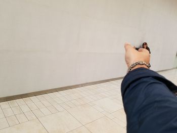 Cropped hand reaching woman against wall