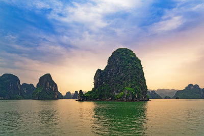 Scenic view of rocky islet in ha long bay during sunset