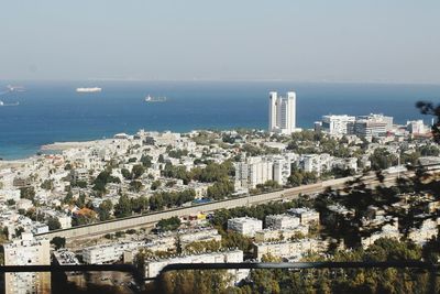 High angle view of cityscape by sea against clear sky