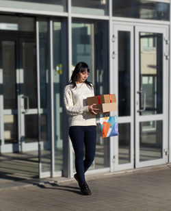 Young woman with gift boxes and purchases leaves the mall. selective focus