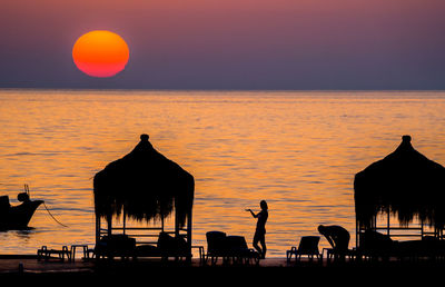 Silhouette of people at hotel against sea during sunset