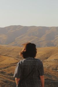 Rear view of woman looking at mountains against sky