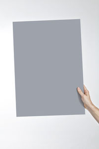 Close-up of hand holding paper against white background