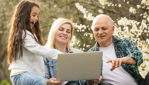 Family enjoying watching laptop in park
