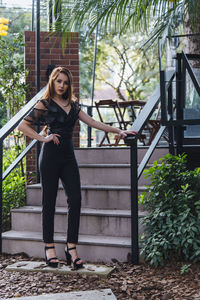 Portrait of young woman standing against railing