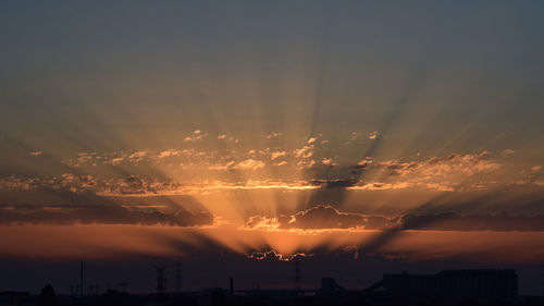 Silhouette city against dramatic sky during sunset