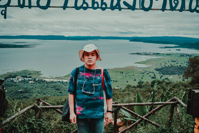 Portrait of boy standing on railing against sea