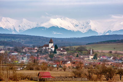 Scenic view of townscape by mountains against sky