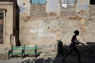 Woman walking against weathered wall