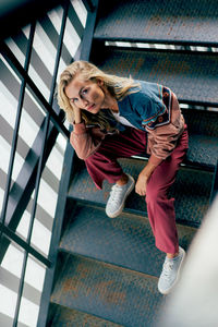 Cheeky modern woman looking at camera while sitting on steps person