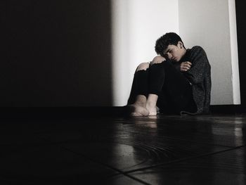 Young couple sitting against wall