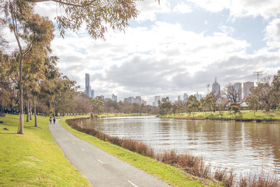 Park by river in city against sky