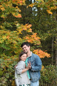 Young couple standing against plants