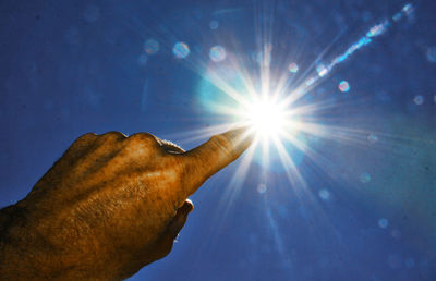 Low angle view of hand against bright sun