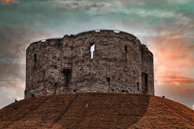 Low angle view of fort against cloudy sky