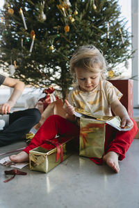 Girl opening christmas presents under christmas tree  barefoot