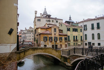 Bridge over river amidst buildings in city against sky