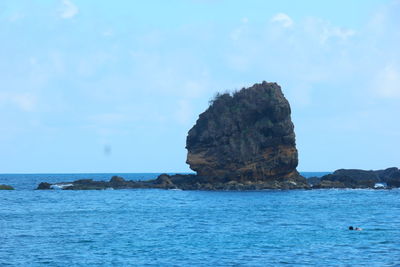 Rock formation in sea against blue sky