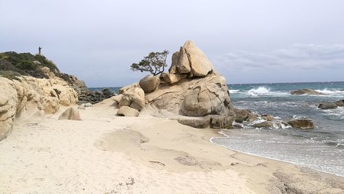 Rock formations on beach against sky