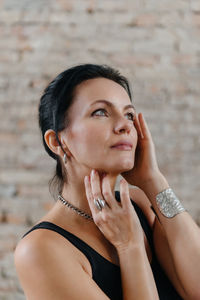 Beautiful middle aged women in black classic outfit, urban location, brick wall. portrait of adult