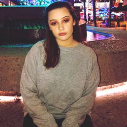 Portrait of young woman standing in city at night