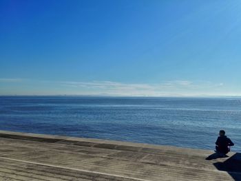 Low section of man on beach against clear blue sky