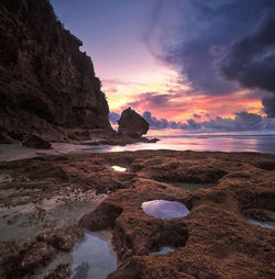 Rock formation on beach against sky during sunset