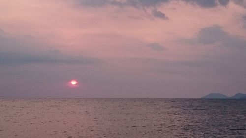 Scenic view of sea against cloudy sky during sunset