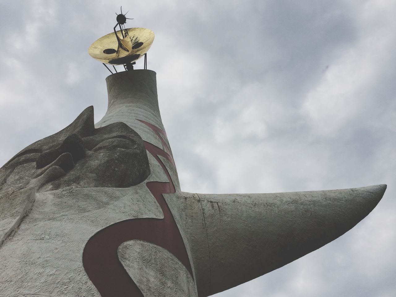 low angle view, sky, cloud - sky, cloudy, cloud, built structure, architecture, building exterior, sculpture, day, outdoors, part of, art and craft, high section, no people, art, tall - high, creativity, tower, flag