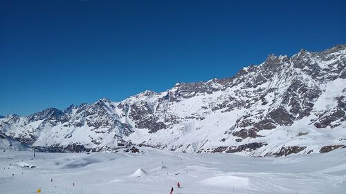 Scenic view of snowcapped mountains against clear blue sky