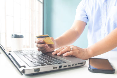 Midsection of woman using laptop on table