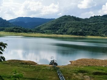 Scenic view of lake by mountains against sky