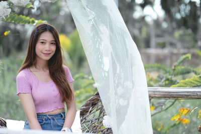 Portrait of young woman standing against trees