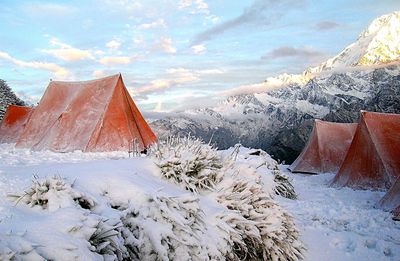 Tents on snow covered field against sky