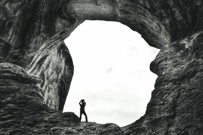 Low angle view of person lifting stone while standing on rock formation