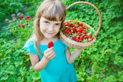 Smiling girl holding strawberries in basket