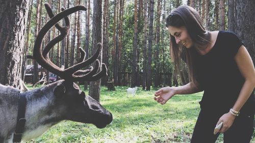 Woman standing by reindeer in forest