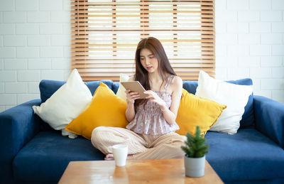 Woman sitting on sofa at home