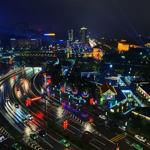 High angle view of illuminated street amidst buildings in city at night