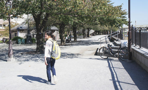 Woman on footpath by street in city