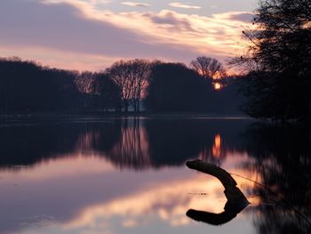 Silhouette trees by lake against sky during sunset