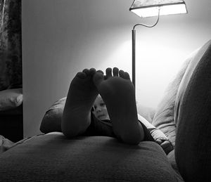 Low section of woman relaxing on bed at home