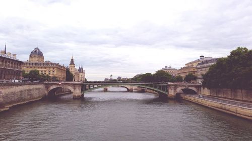 Bridge over river against cloudy sky