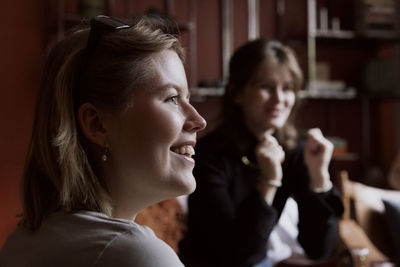 Smiling young woman with friend in apartment