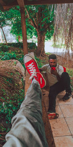 Low section of man relaxing on tree trunk in forest