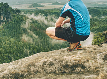 Runner on the peak. hiker in running trousers and shinning blue sweaty t-shirt. man in his target.