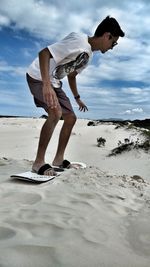 Full length of boy standing on beach against sky