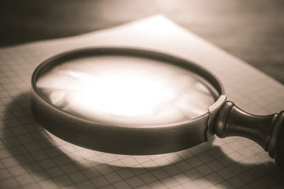 High angle view of magnifying glass with book on wooden table